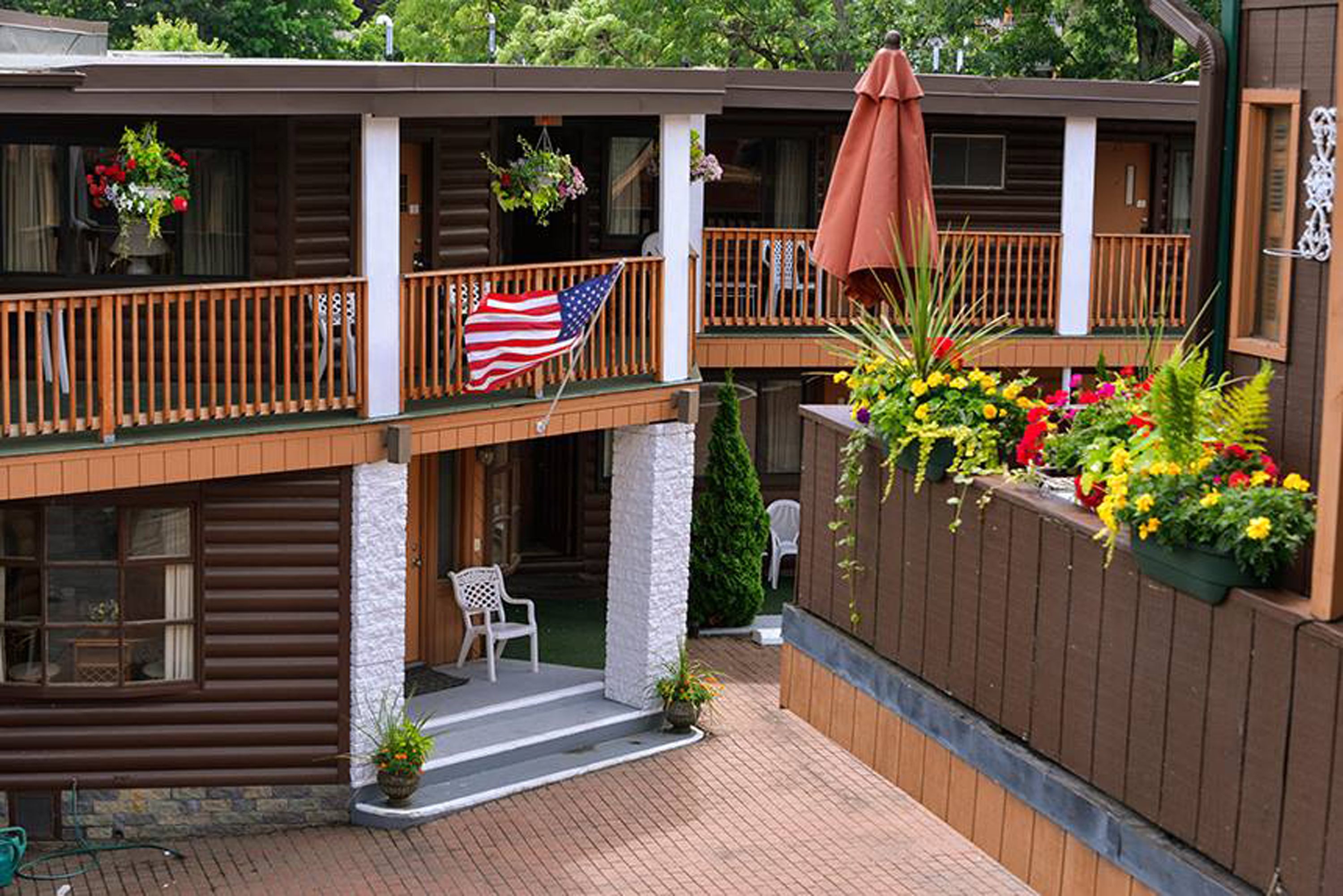 Een tweelaags landhuis met een balkon, buitenmeubels en een vlag.