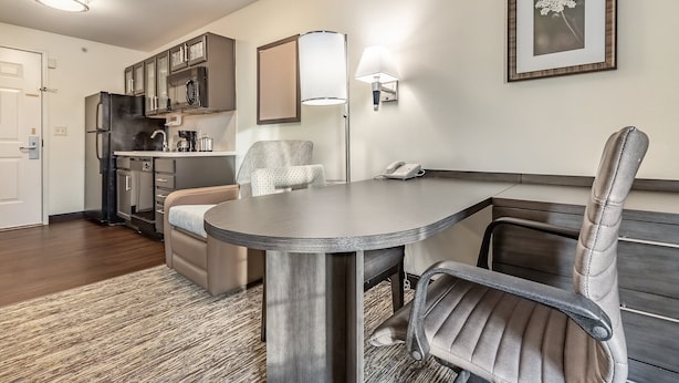 A compact kitchen with modern appliances, a dining area with a bench, and a framed picture on the wall.