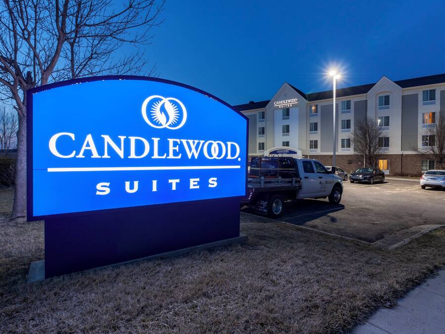 A hotel sign with 'CANDLEWOOD SUITES' and a building with multiple windows in the background.