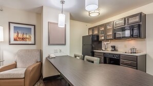 A modern kitchen with a dining area, including a long table, chairs, and a sofa.