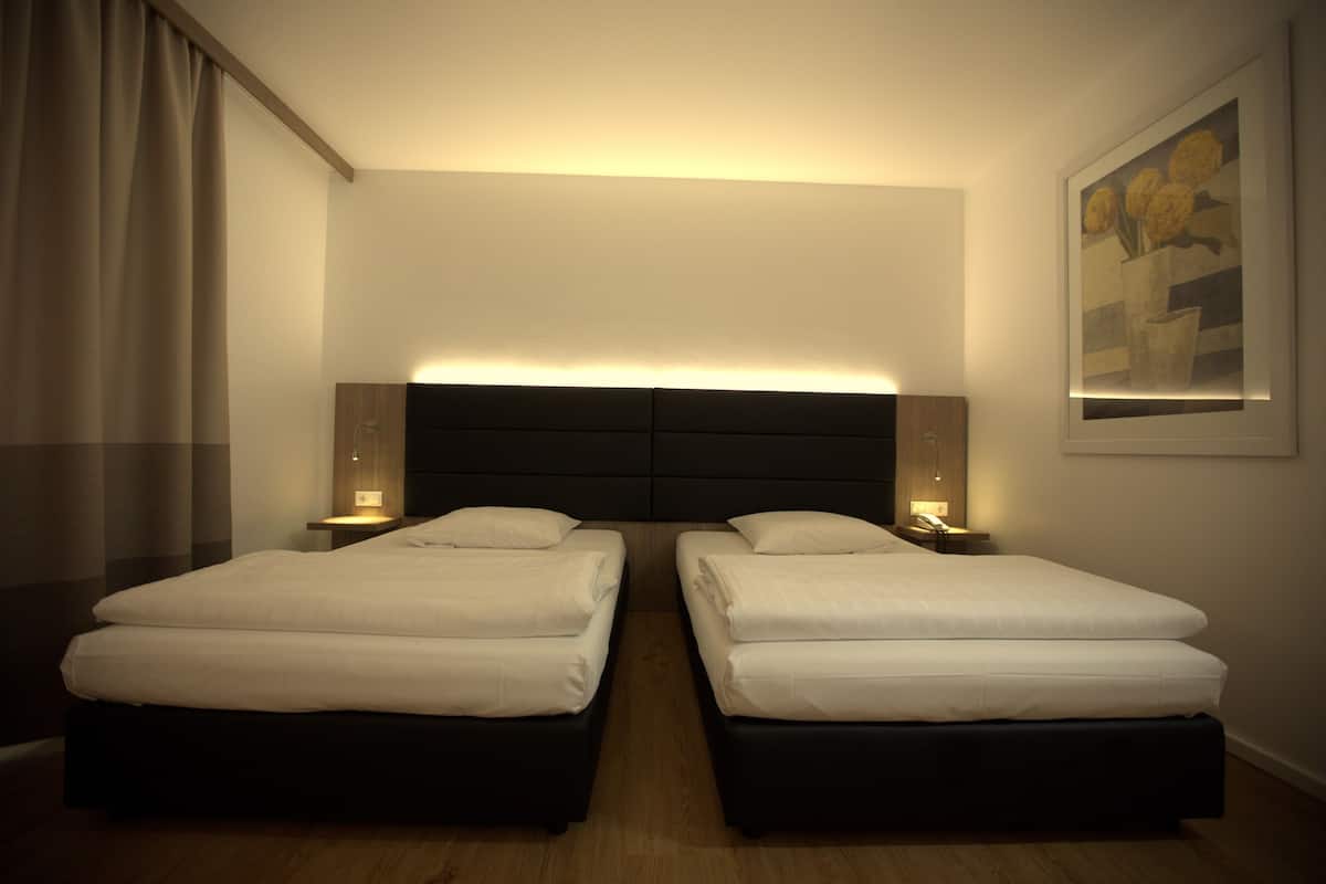 Una habitación de hotel con dos camas, piso de madera y un cuadro en la pared.