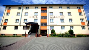 A multi-story hotel with "HOTEL WALLDORF" signage, a covered entrance, and a paved driveway. - Airport Hotel Walldorf (Moerfelden-Walldorf)
