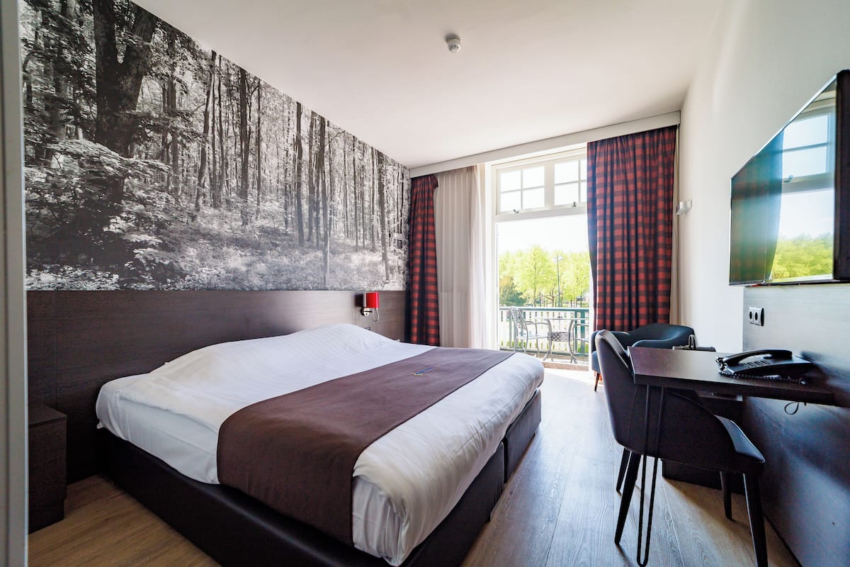 Ein modernes Hotelzimmer mit einem großen Bett, einem Schreibtisch und Blick ins Freie.