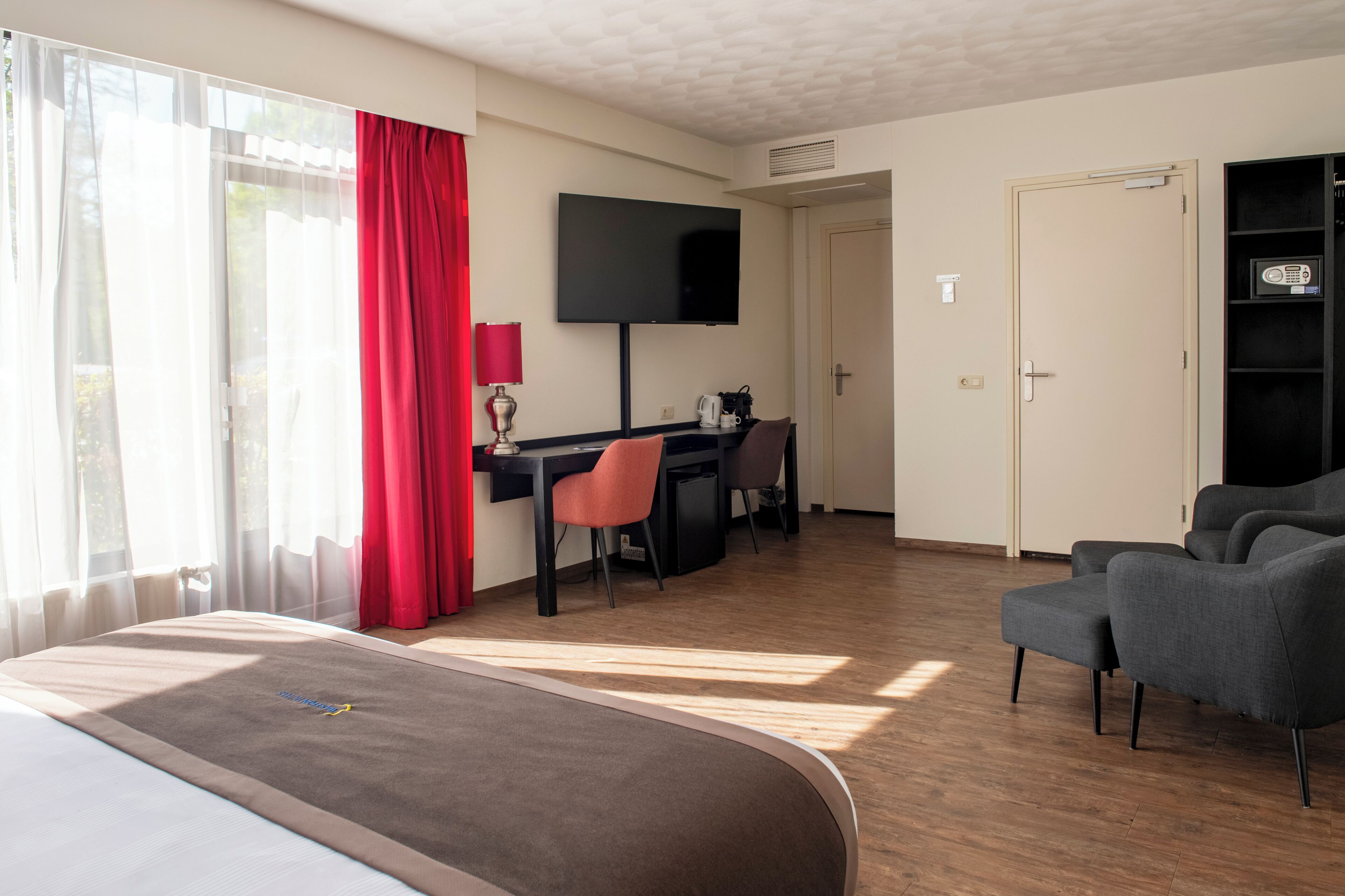 A hotel room with a bed, desk, chair, TV, and a bookshelf.