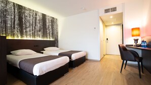A hotel room with two beds, a desk, and a chair. - Bastion Hotel Apeldoorn Het Loo (Apeldoorn)