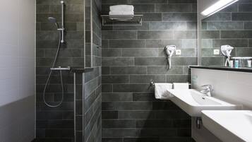 Un baño moderno con ducha, dos lavamanos y un perchero para toallas.