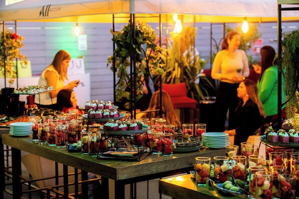 A buffet table with various food items and drinks, surrounded by guests. - Mercure Santiago Centro (Santiago)