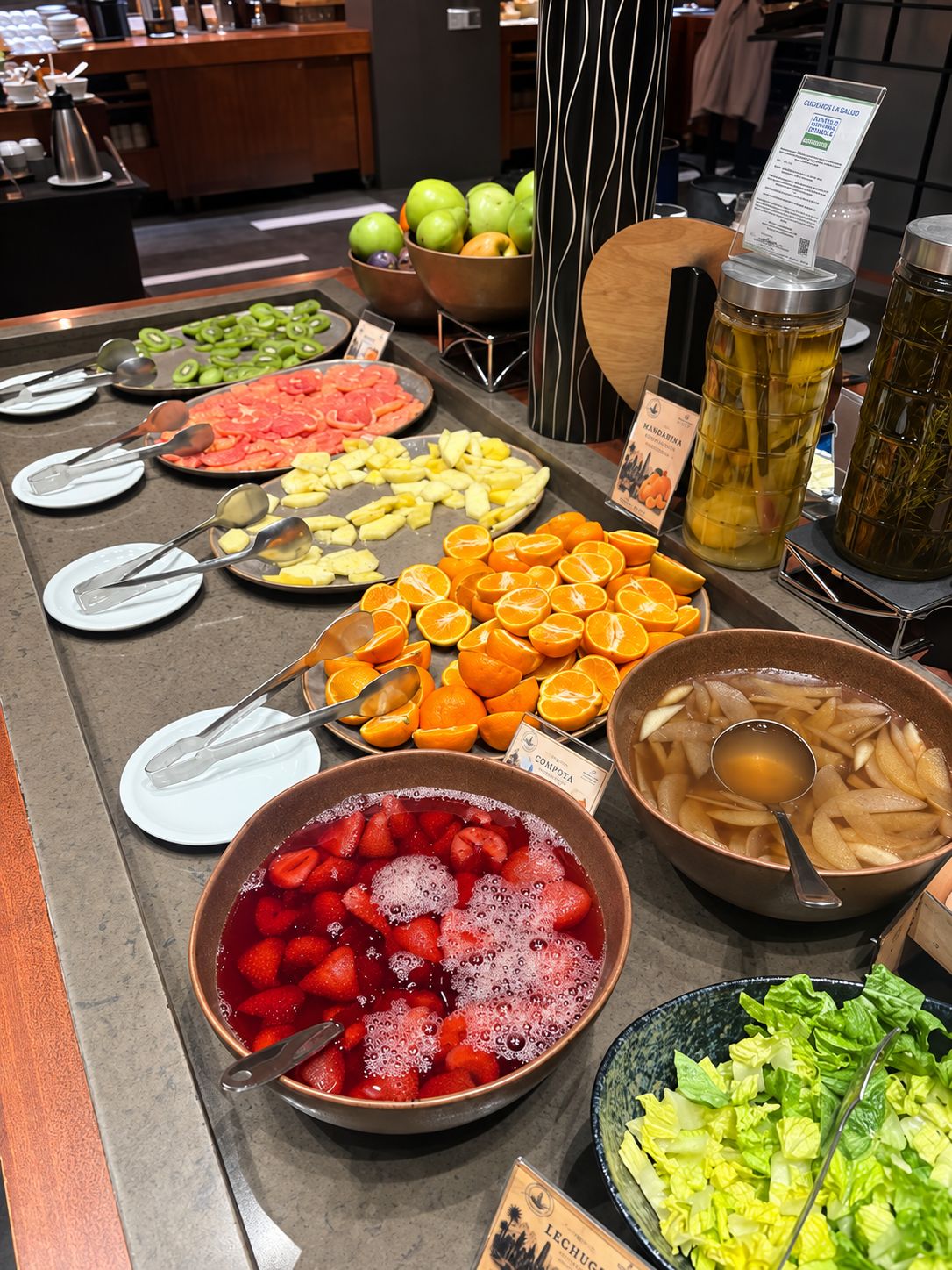 A buffet with various fruits and vegetables, including strawberries, oranges, and green apples.