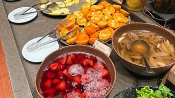 A buffet with various fruits and vegetables, including strawberries, oranges, and green apples.
