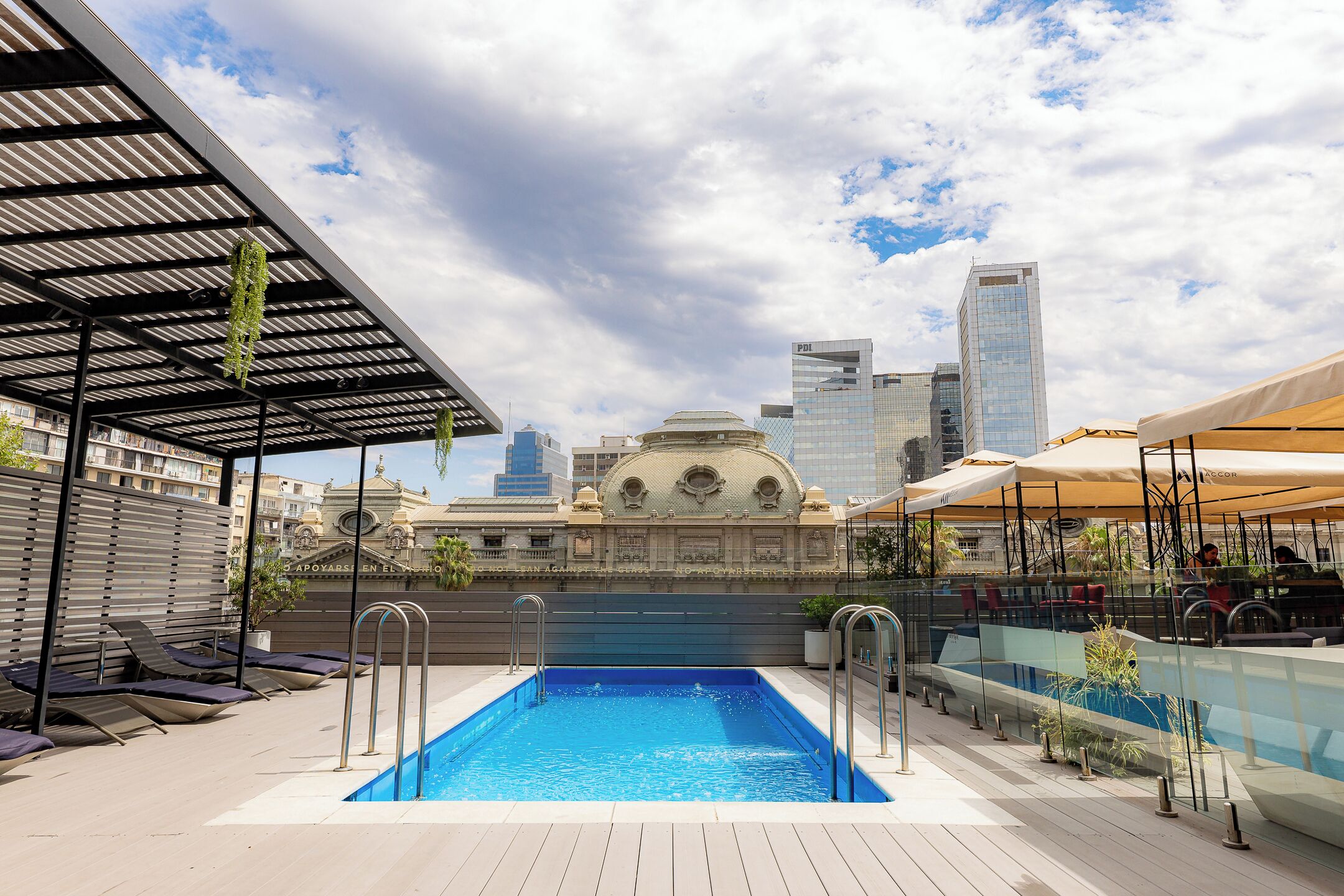 A rooftop pool with a view of a historic building and modern skyscrapers.