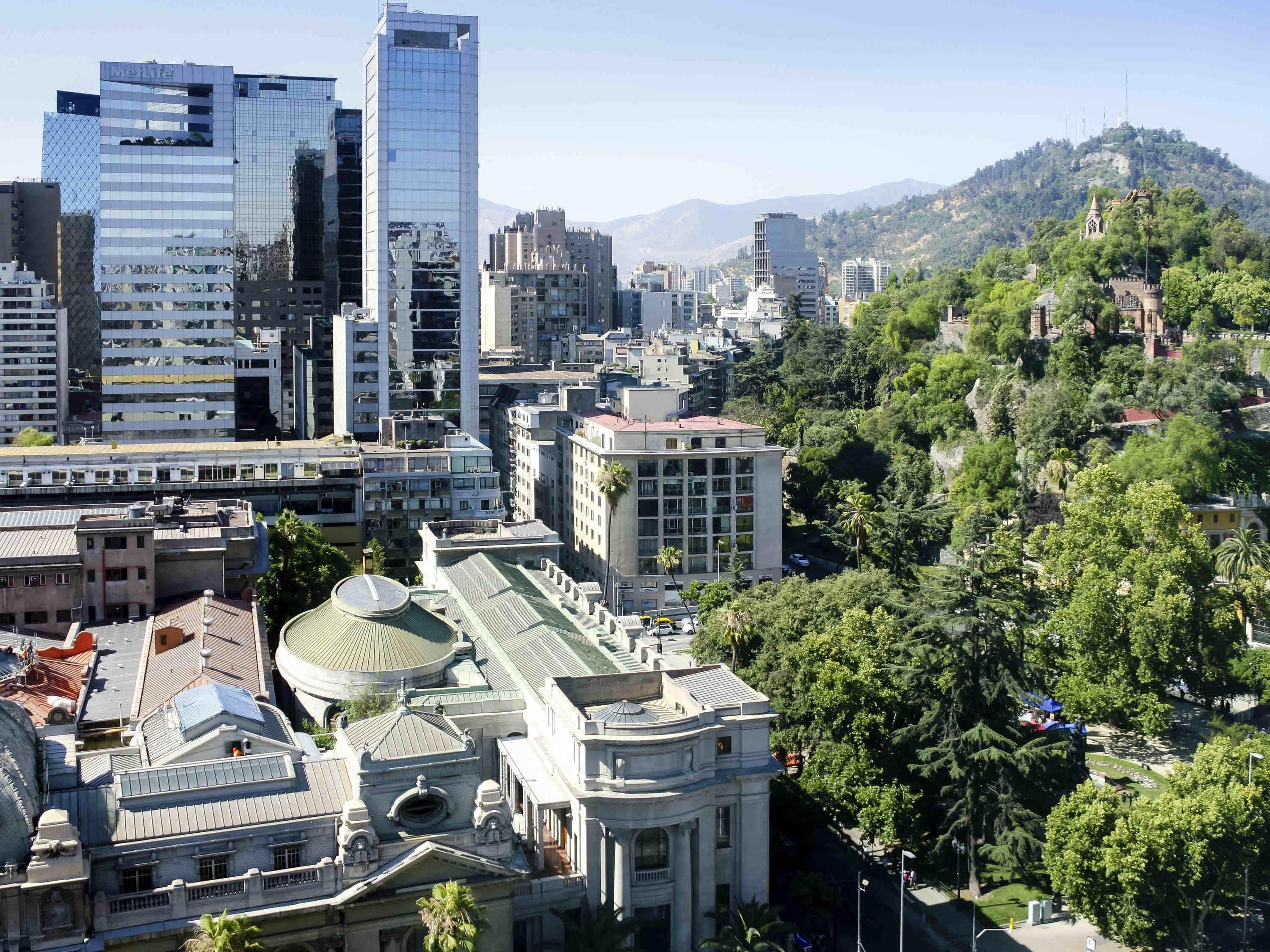 A cityscape with modern and historic buildings, including a prominent glass skyscraper and a classical building with a dome.