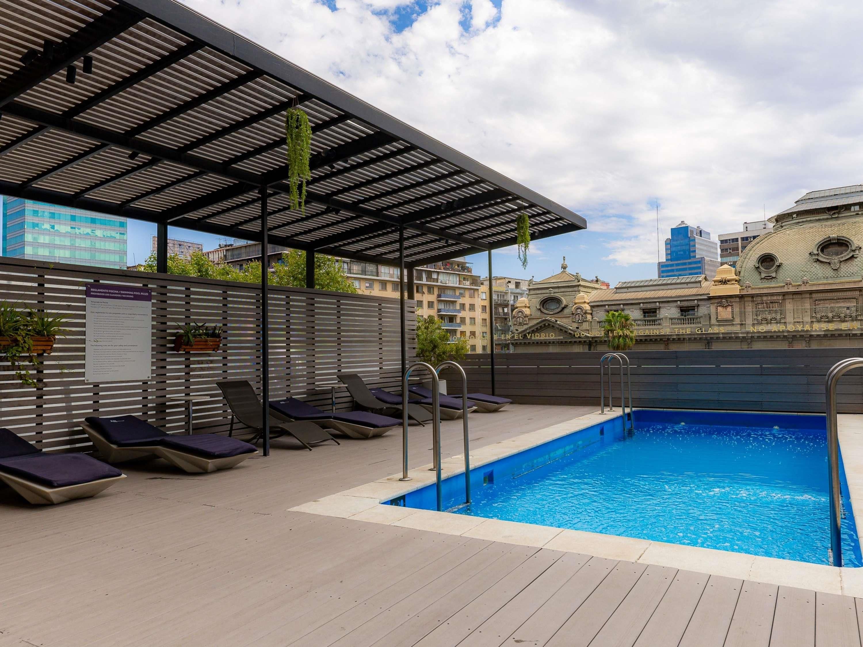 A rooftop pool area with lounge chairs and a pergola.