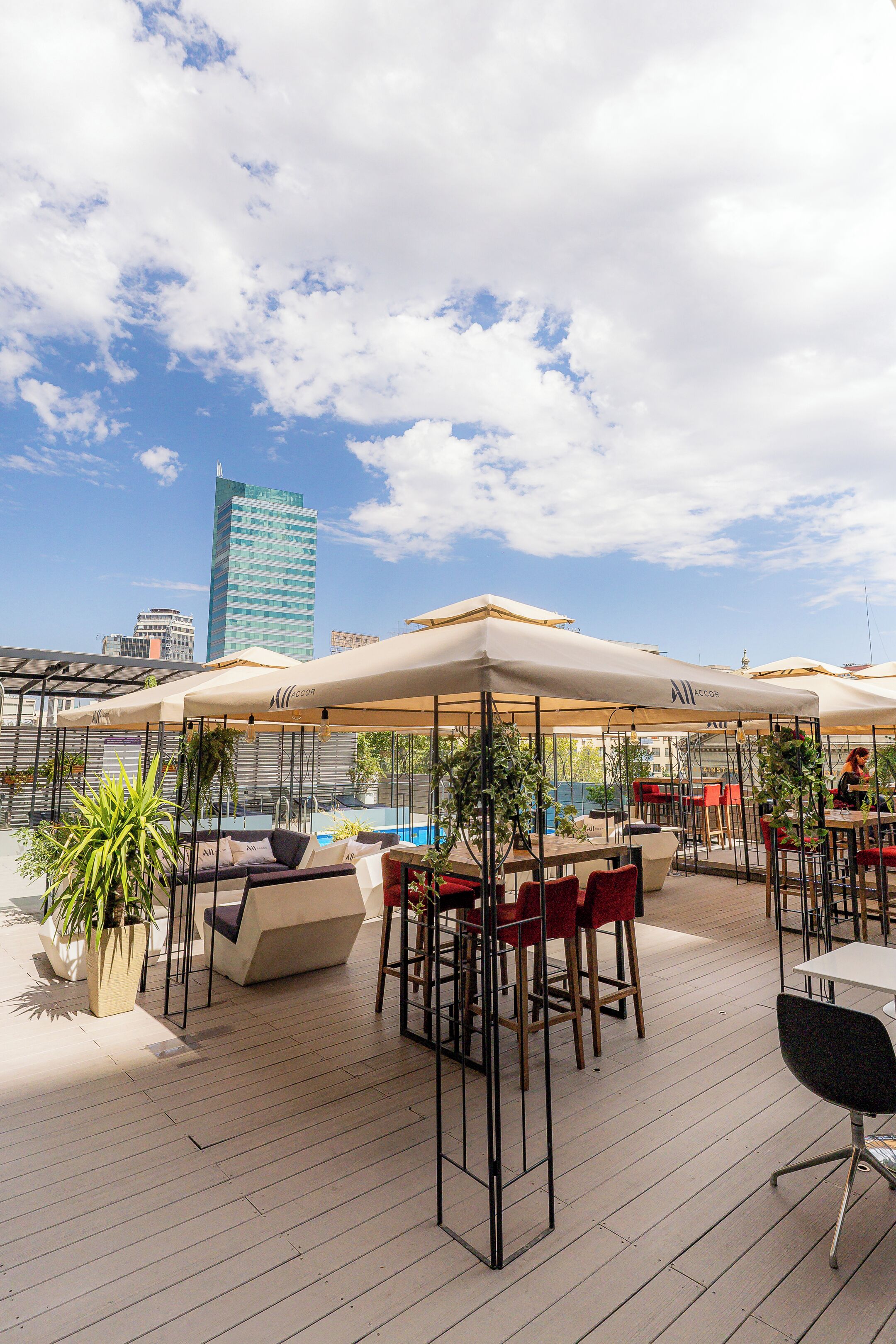 An outdoor seating area with umbrellas, tables, and chairs, overlooking a pool.