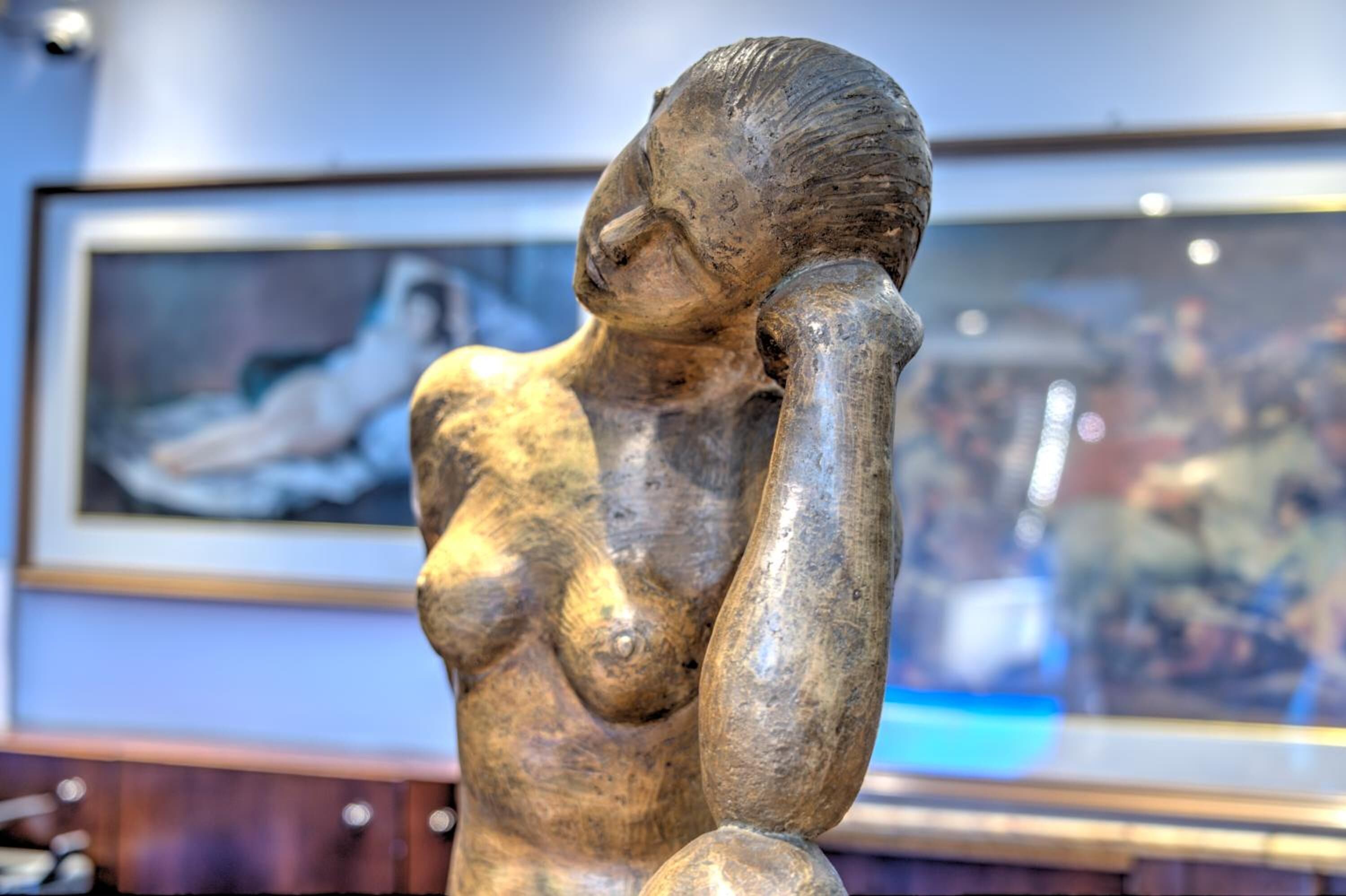 A sculpture of a reclining figure in a museum setting.