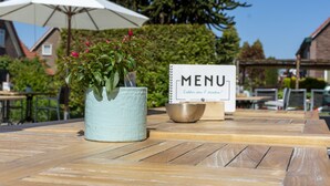Una mesa de madera con un cartel de menú y una planta en maceta.