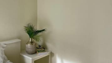 Une chambre à coucher avec un lit, une table de chevet et une plante en pot.