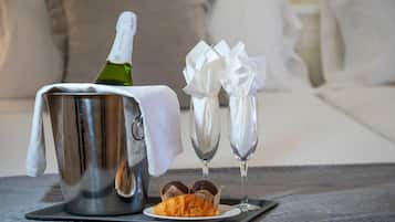 Una bottiglia di champagne, due bicchieri e un croissant su un vassoio.
