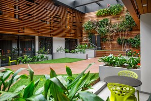 Relax in a serene outdoor space with a seating area, potted plants, and a slatted wall.