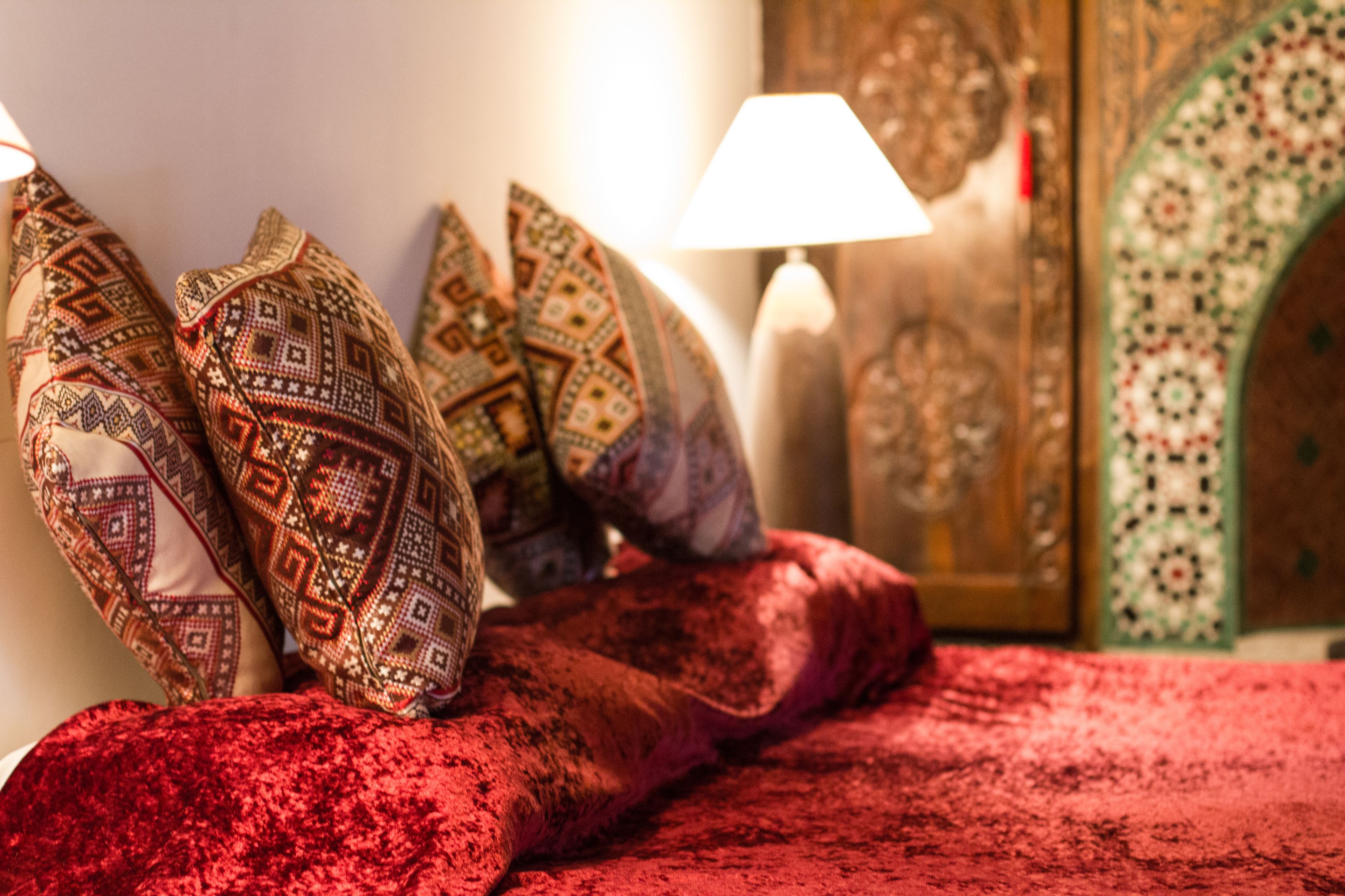 Una cama con almohadas estampadas y una manta roja.