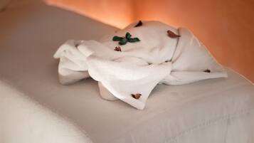 A neatly folded white towel on a bed with a textured surface.