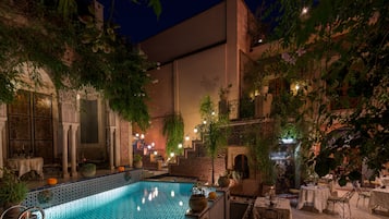 Relax by the tranquil water feature surrounded by lush greenery and traditional architecture.