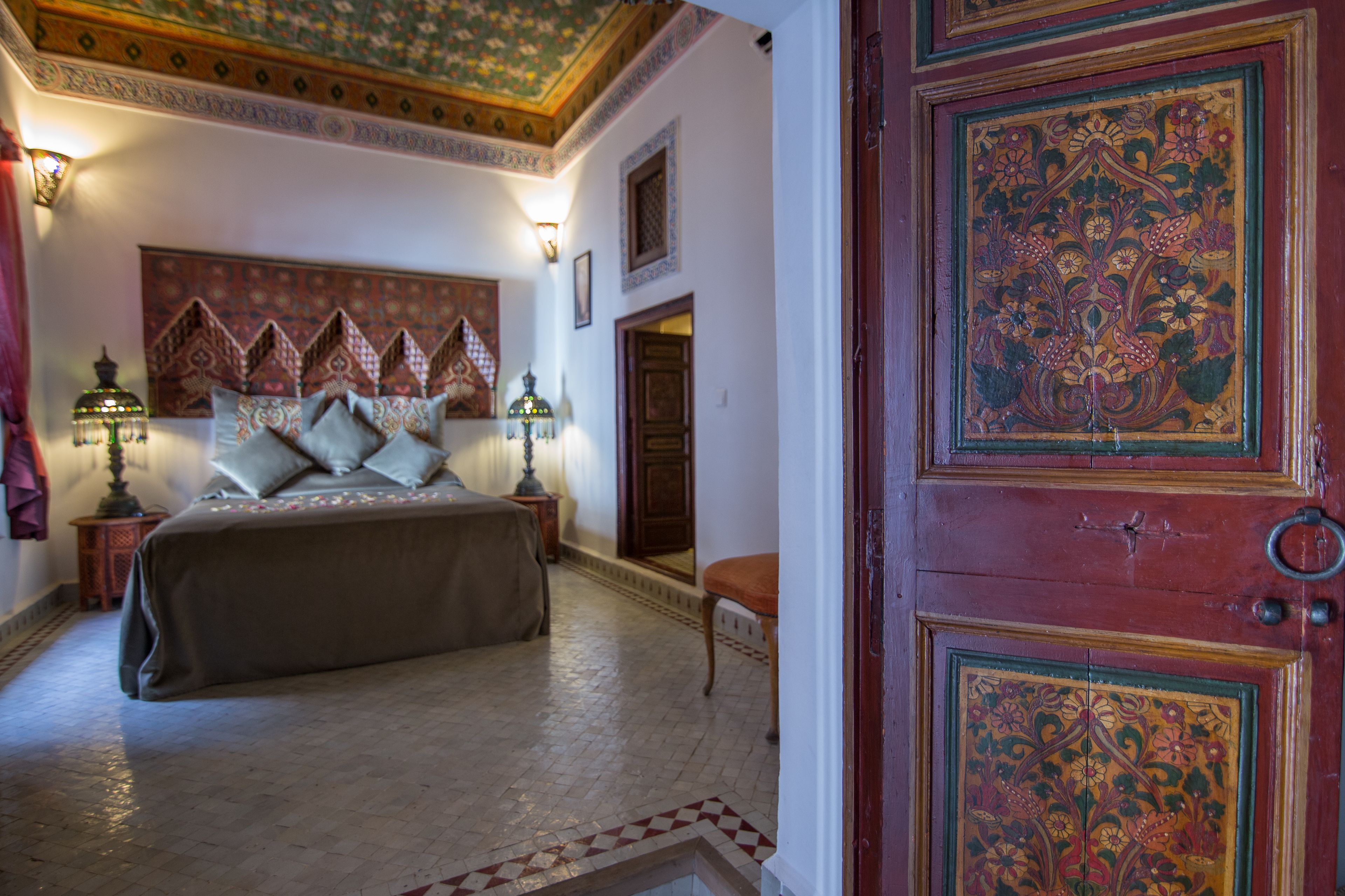Una habitación tradicional con cama, mesitas de noche y un detalle decorativo en la pared.