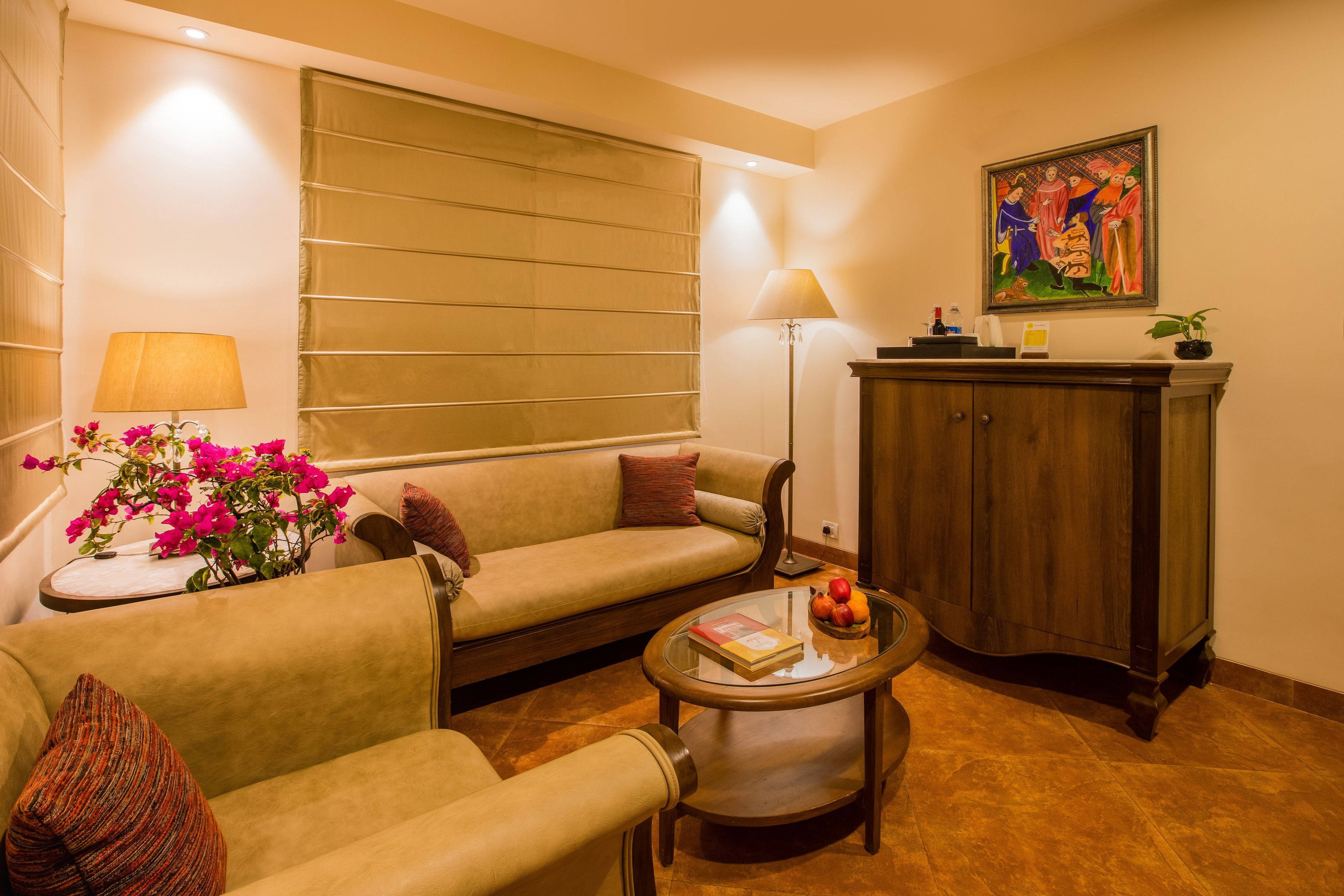 Una sala de estar acogedora con un sofá, sillones, una mesita de centro de vidrio y un aparador de madera.