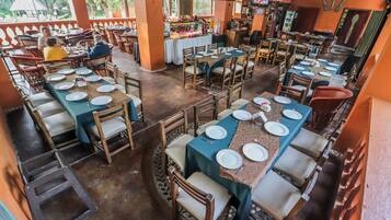 Un restaurante con varias mesas dispuestas, con platos y cubiertos, rodeado de sillas de madera.