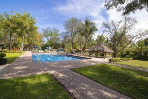 Una piscina al aire libre, sillones reclinables de piscina