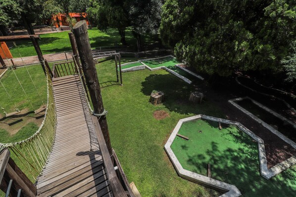 A wooden bridge over a grassy area with a small pond and a wooden deck.