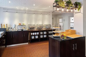 Una cocina moderna con estaciones de comida tipo buffet, un lavamanos y un cuenco de frutas.