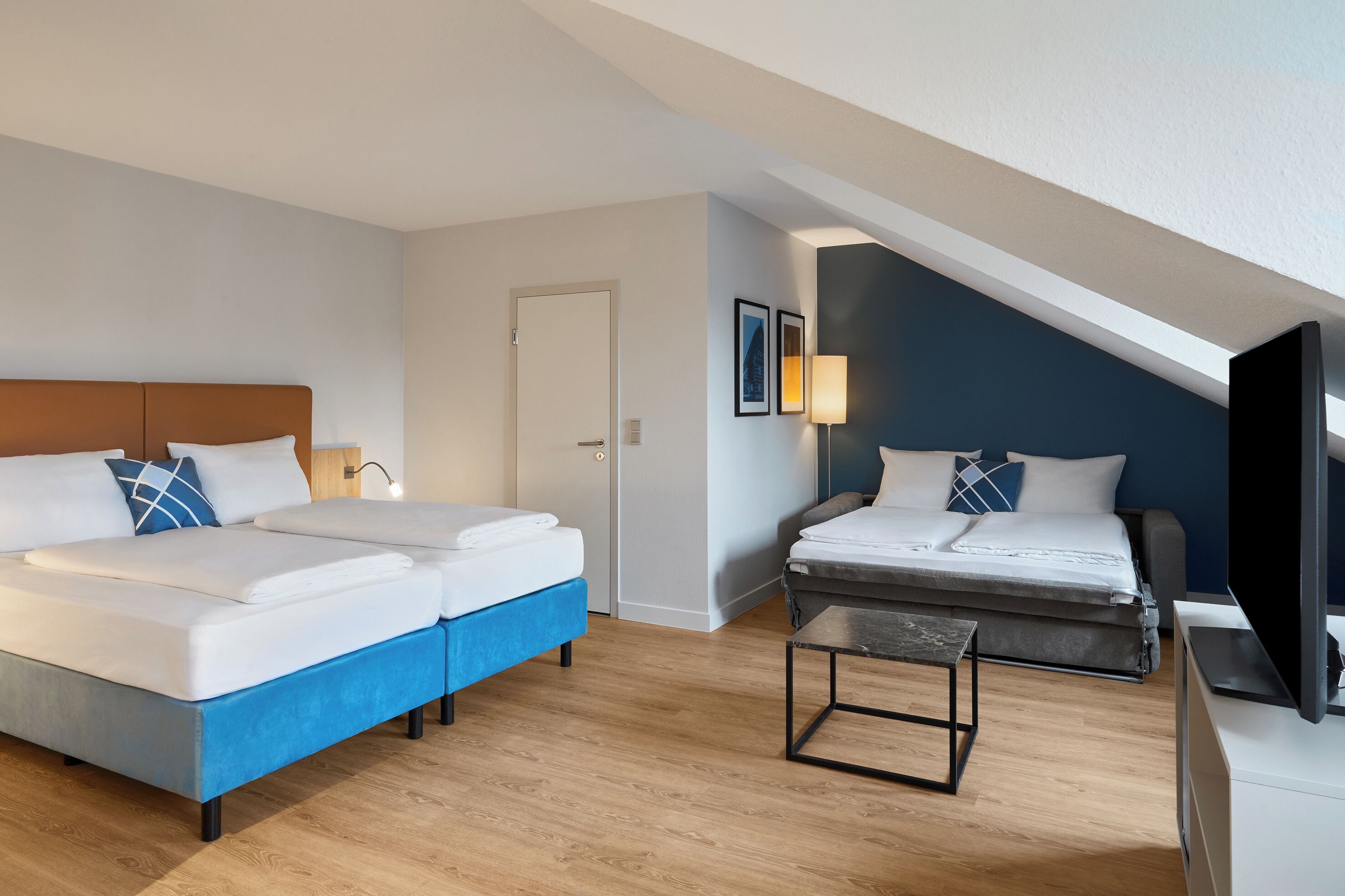 Ett hotellrum med två sängar, en TV, ett skrivbord och en dörr.