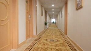 A long, narrow hallway with ornate carpet, wooden doors, and a ceiling with recessed lighting. - GreenTree Inn Guangdong Shenzhen Dongmen Business Hotel (Shenzhen)