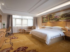 A hotel room with a large bed, a desk, a chair, and a painting on the wall. - GreenTree Inn Guangdong Shenzhen Dongmen Business Hotel (Shenzhen)