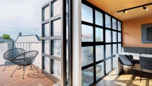 A modern apartment with large windows, a wooden deck, and a dining area. - B&B Hotel München-Hbf (Munich)