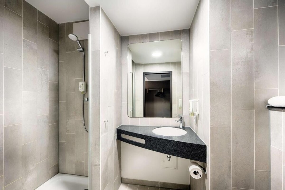 Een moderne badkamer met een douche, wastafel en toilet.