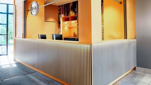 A reception area with a B&B sign, a counter, and a seating area with chairs. - B&B Hotel München-Hbf (Munich)