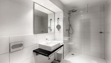 Ein modernes Badezimmer mit Waschbecken, Spiegel und Duschbereich in Weiß.