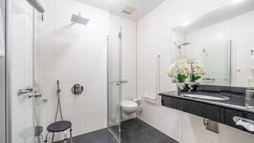 A modern bathroom with a glass-enclosed shower, a toilet, and a sink with a black countertop.