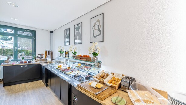 Un buffet de petit-déjeuner proposant divers aliments, un grille-pain et une fenêtre donnant sur un espace verdoyant.