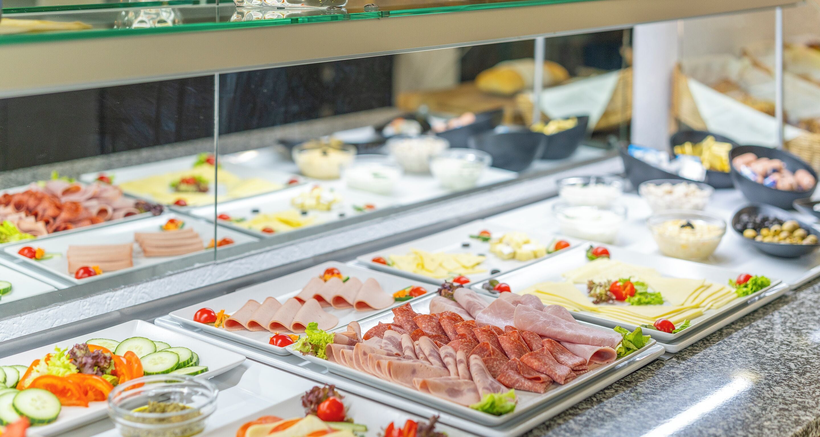 Ein Buffet mit verschiedenen Speisen, darunter Fleisch, Käse und Salate.