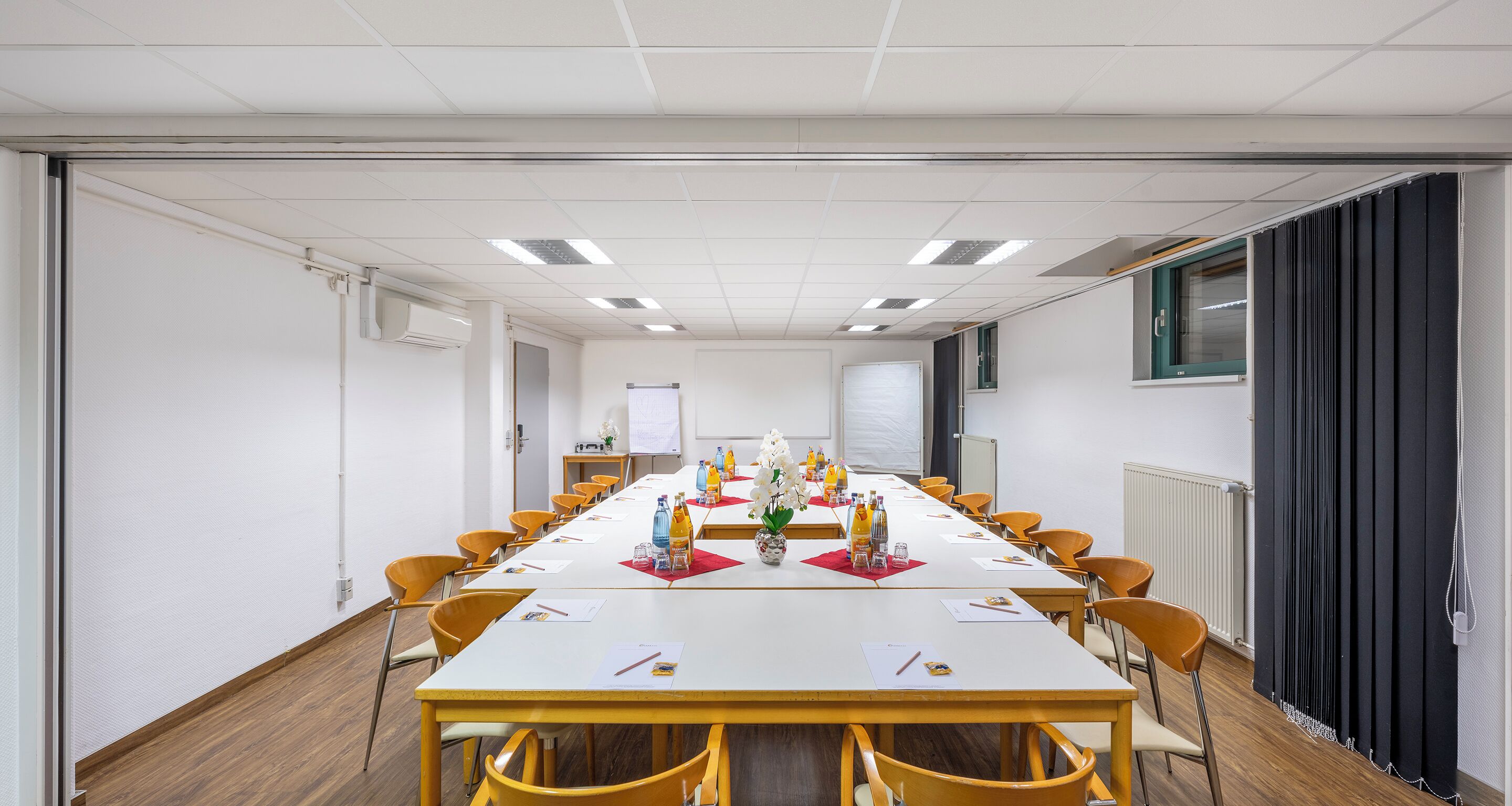 Una sala de conferencias con una mesa larga, sillas amarillas y una pizarra.