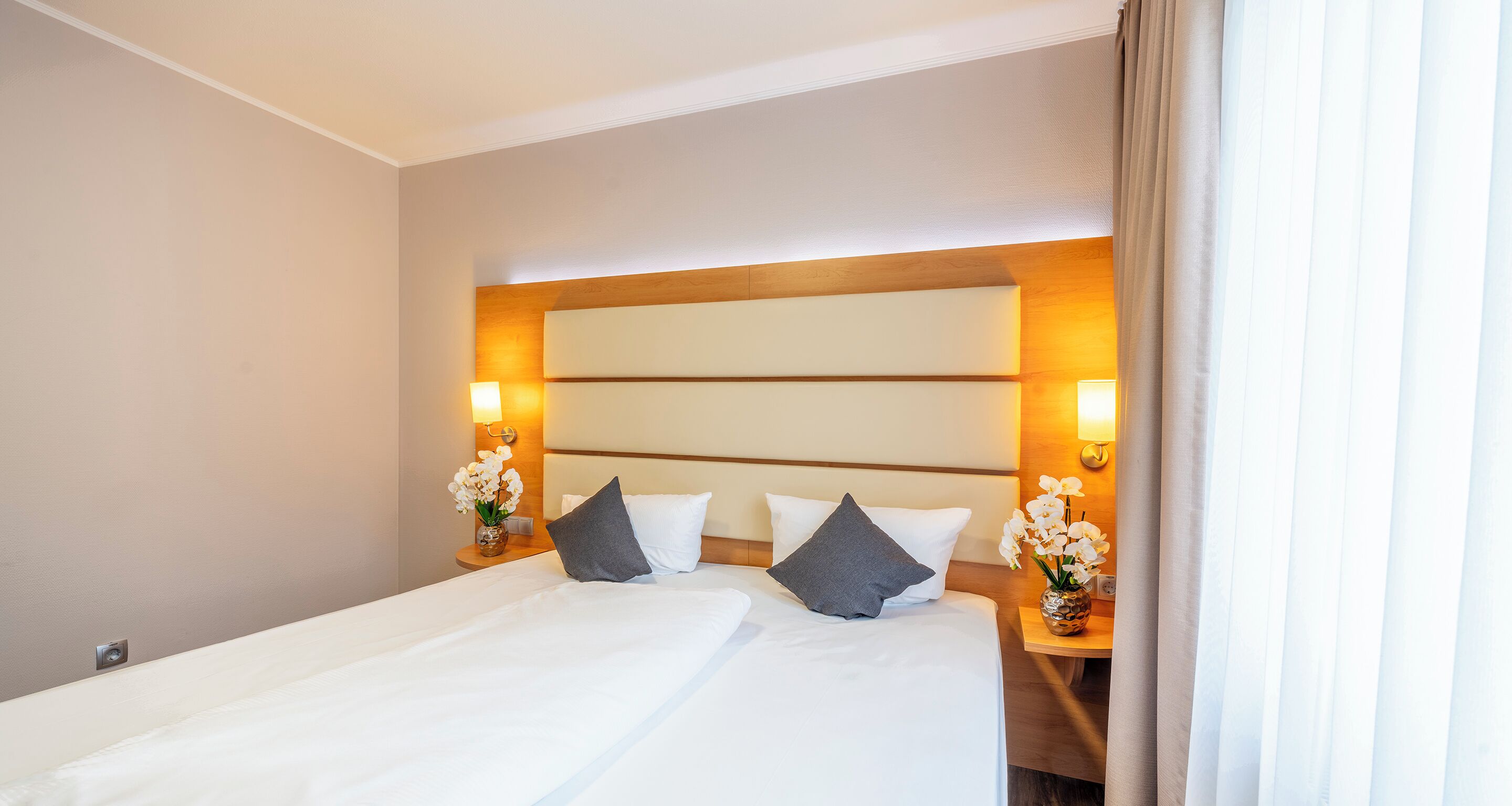 Una habitación de hotel con una cama grande, dos mesitas de noche y una mesita de noche con lámpara.