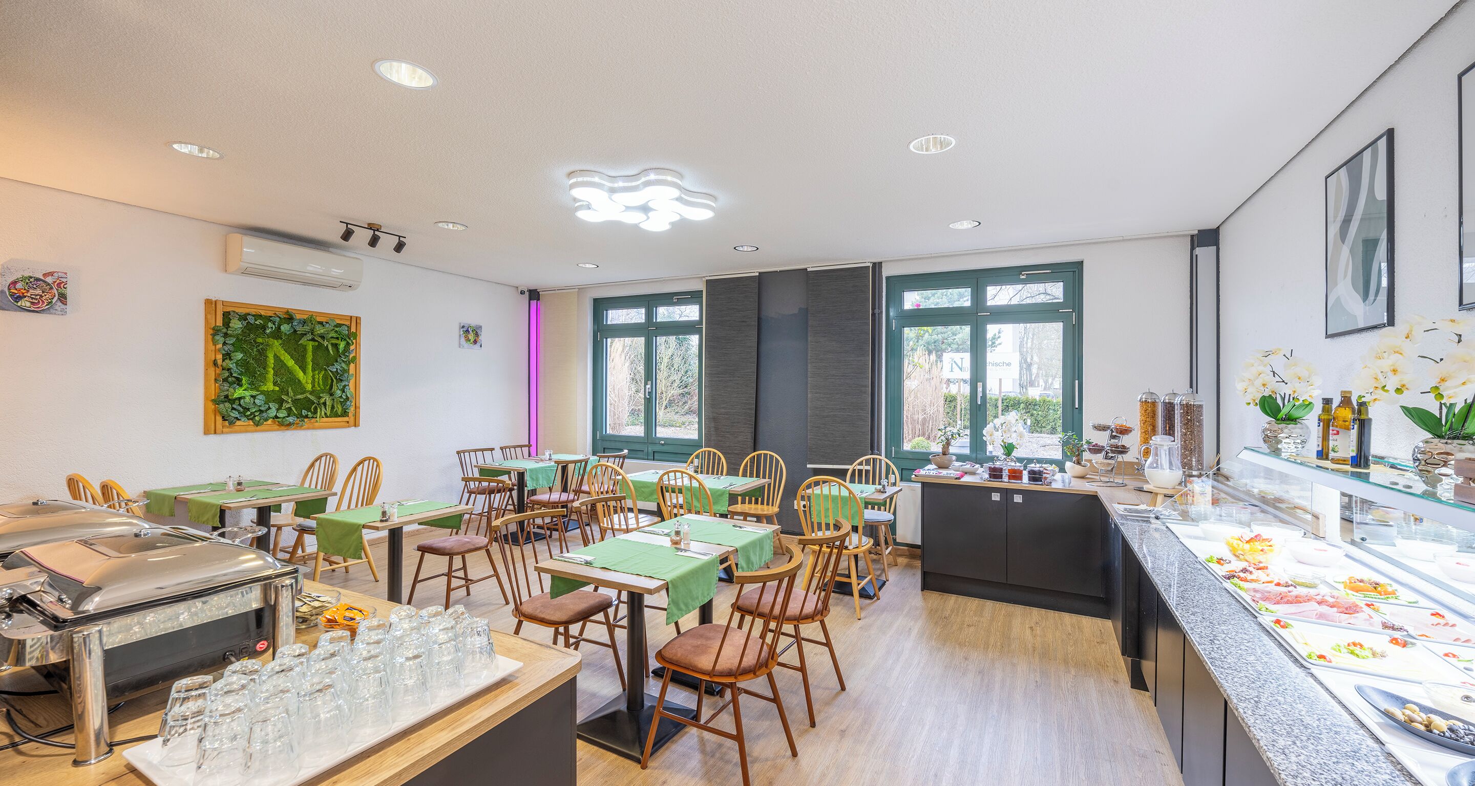A dining area with tables and chairs, a buffet station, and a kitchen counter with food displays.