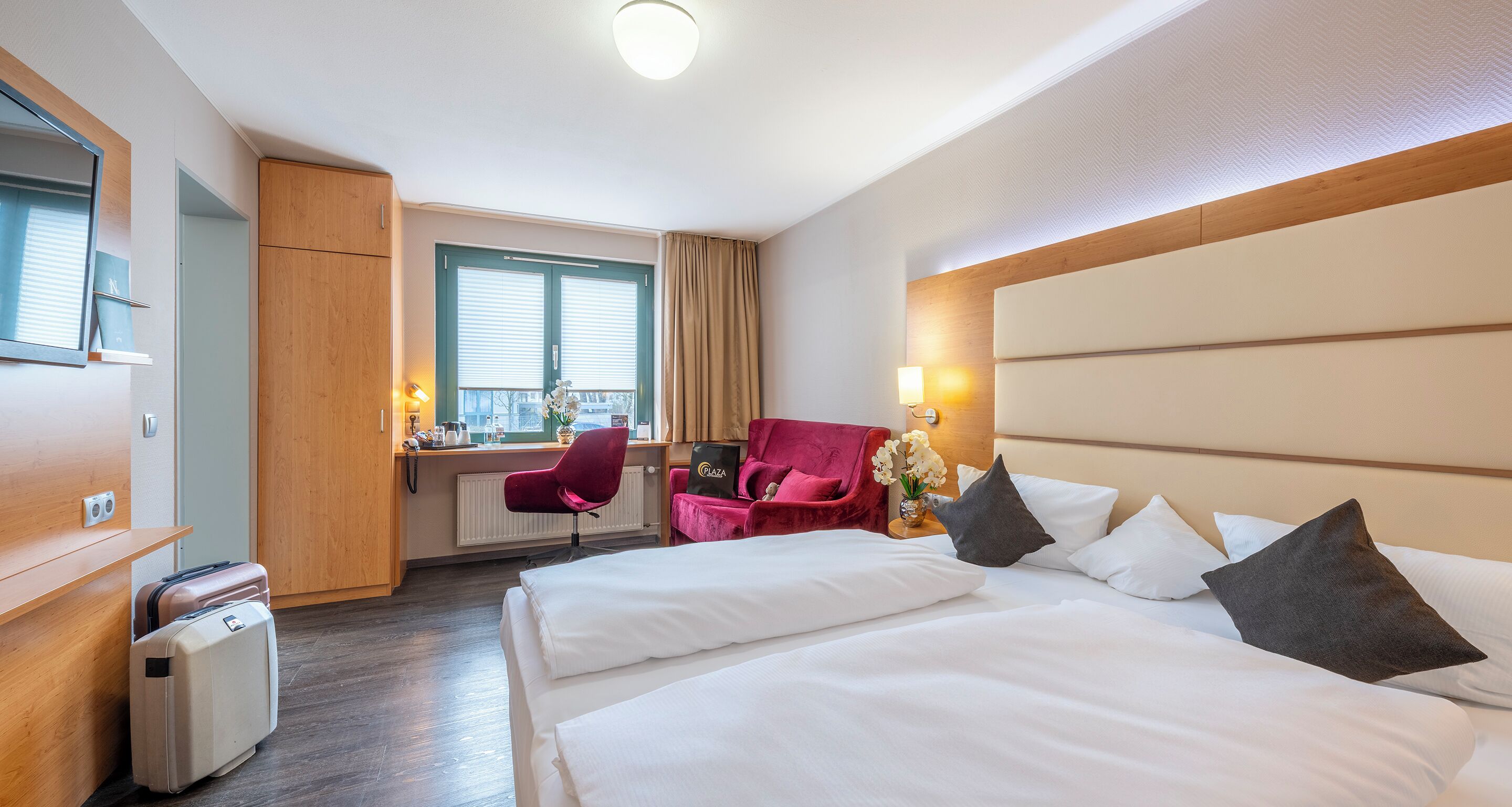 A hotel room with a bed, a desk, a chair, and a minibar.