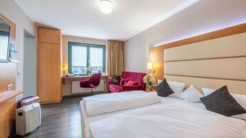 A hotel room with a bed, a desk, a chair, and a minibar.
