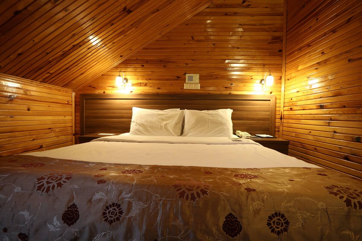 Een kamer met houten lambrisering, een bed, twee bedlampen en een nachtkastje.