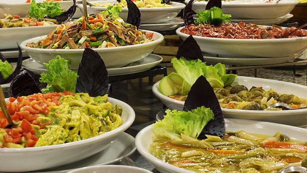 Un buffet proposant divers plats, notamment des salades, des soupes et un choix de boissons.