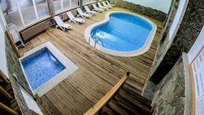 Un espace piscine doté d’un jacuzzi, de chaises longues et d’un mur en pierre.