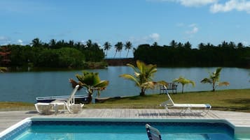 Een buitenzwembad, ligstoelen bij het zwembad